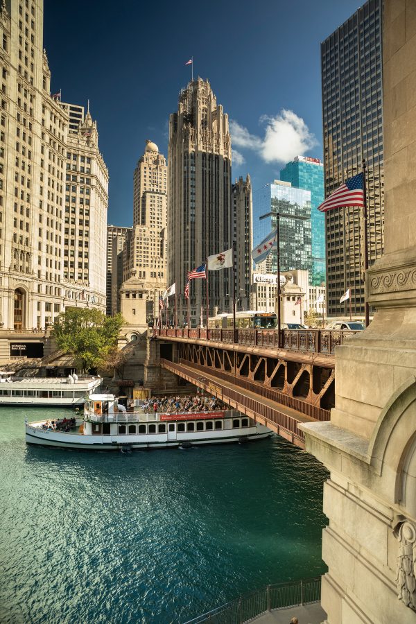 A boat floats along below a bridge spanning the Chicago River.