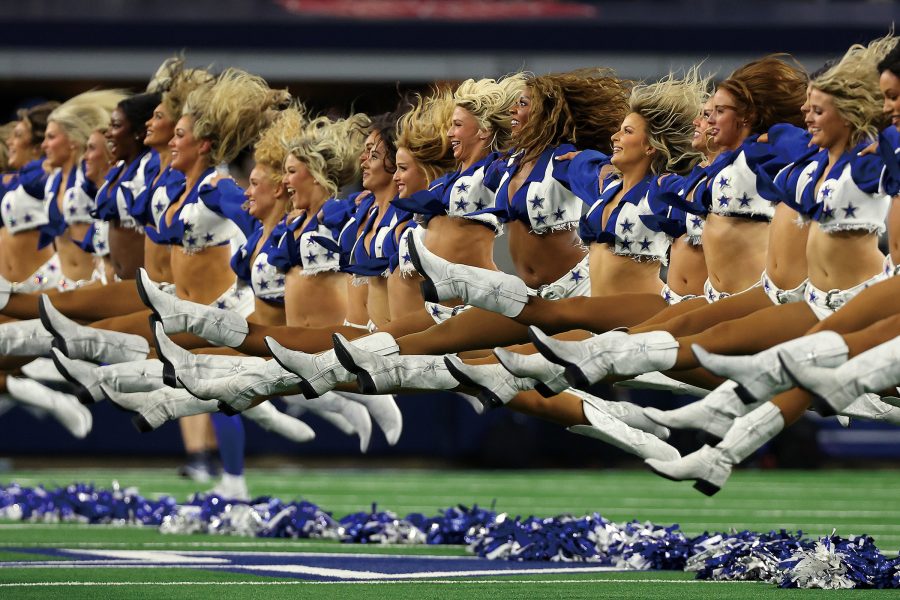 Dallas Cowboys cheerleaders doing jump splits on the field.