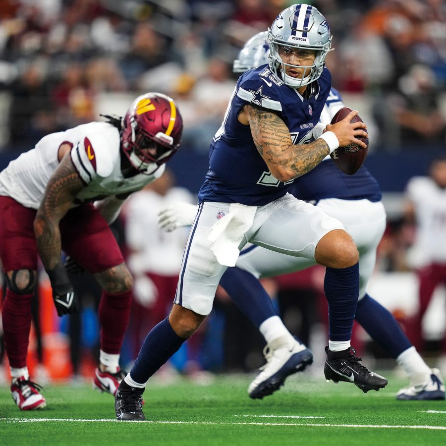 A Dallas Cowboys player running with the football on the field during a game. 