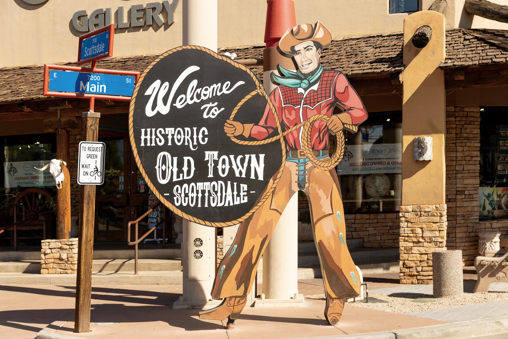 A sign on Main Street depicting a cowboy holding a lasso next to a text bubble that says “Welcome to historic Old Town Scottsdale” in Arizona.