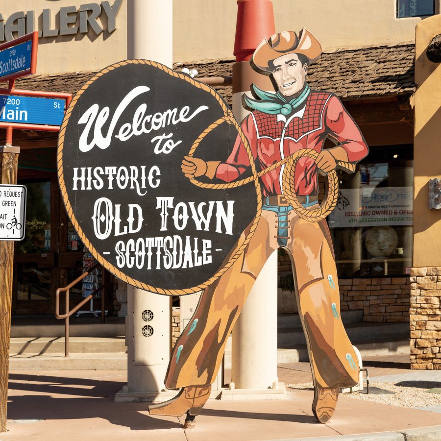 A sign on Main Street depicting a cowboy holding a lasso next to a text bubble that says “Welcome to historic Old Town Scottsdale” in Arizona.
