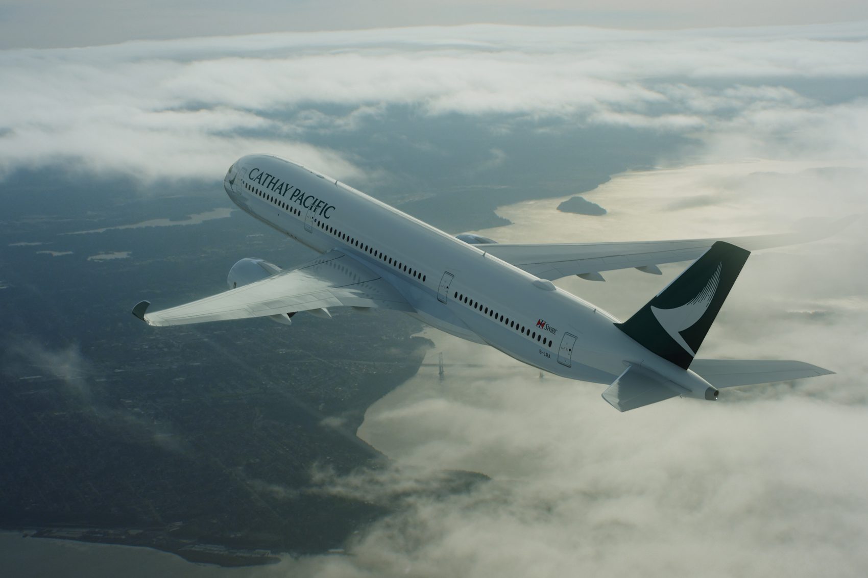 A Cathay Pacific plane flies through the air. Beneath it are clouds and a glimpse of coastline