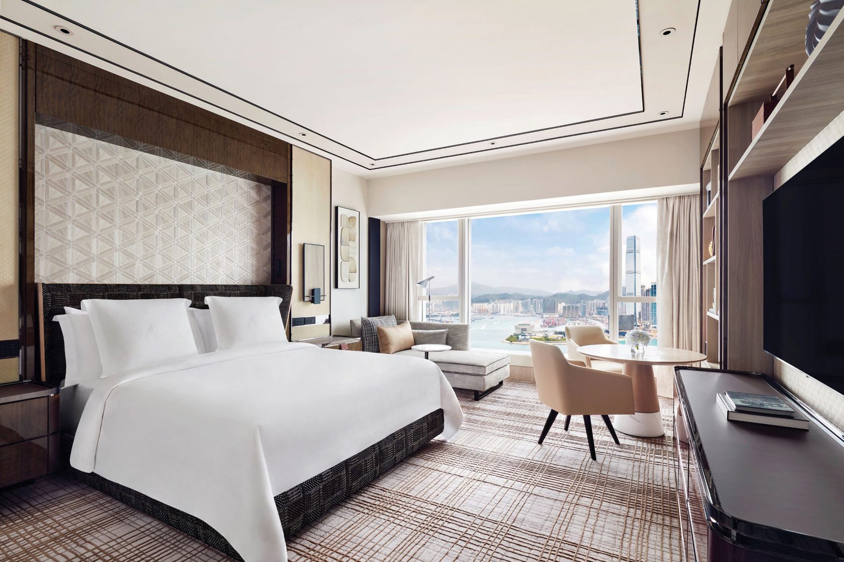 Interior shot of the elegant Four Seasons Hotel Hong Kong guest room with a view of Victoria Harbour during daytime