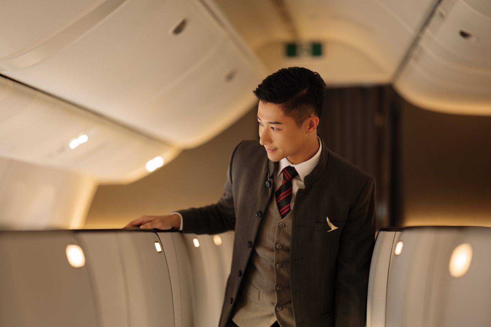 A Cathay Pacific cabin crew member pauses in the aisle and checks a seat in the First Class cabin of a Cathay Pacific plane.