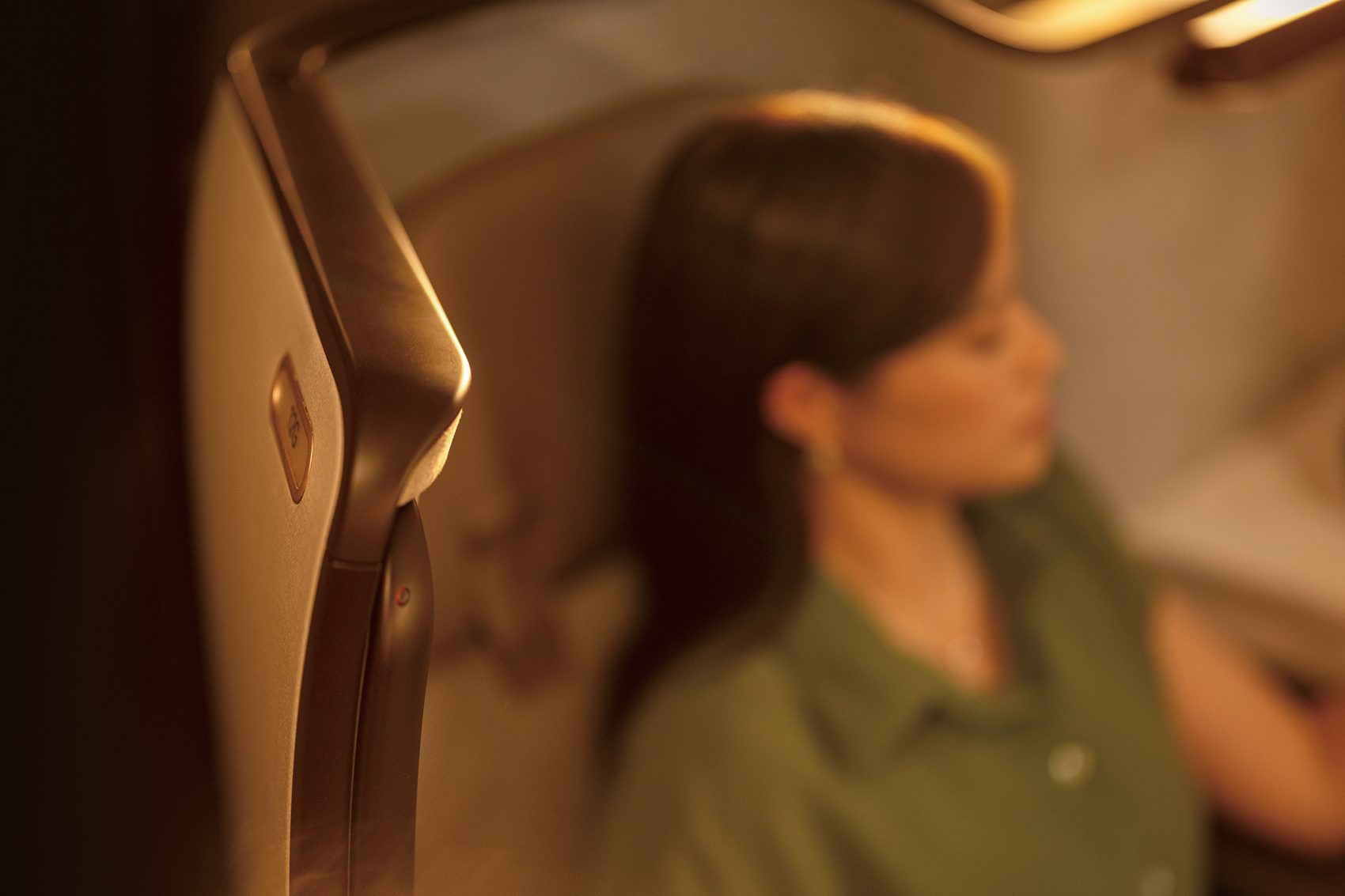 A woman sits with her eyes closed in the First class cabin of a Cathay Pacific plane