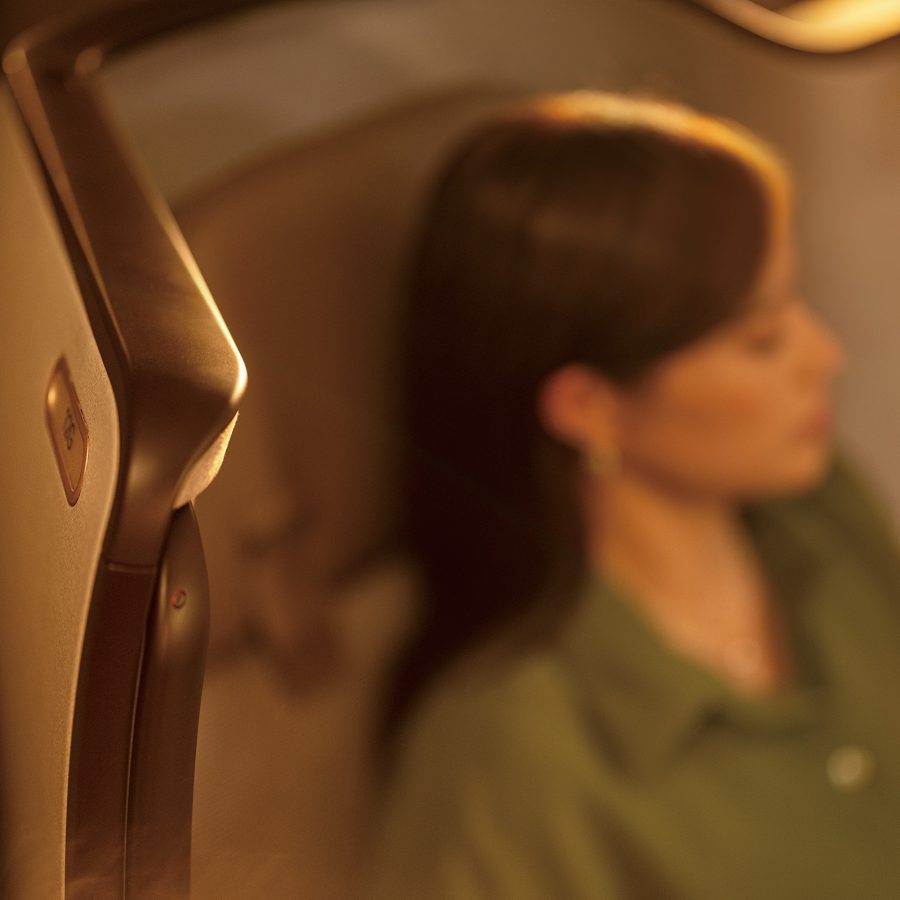 A woman sits with her eyes closed in the First class cabin of a Cathay Pacific plane