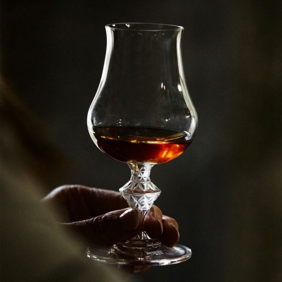 Person holding up a whisky glass with a finger’s worth of whisky in it. 