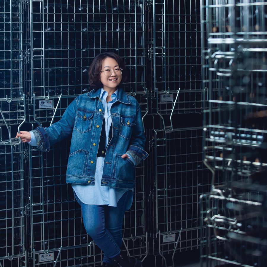 A portrait photo of Helan Qingxue Vineyards’ Zhang Jing smiling in denime standing next to wire grids.