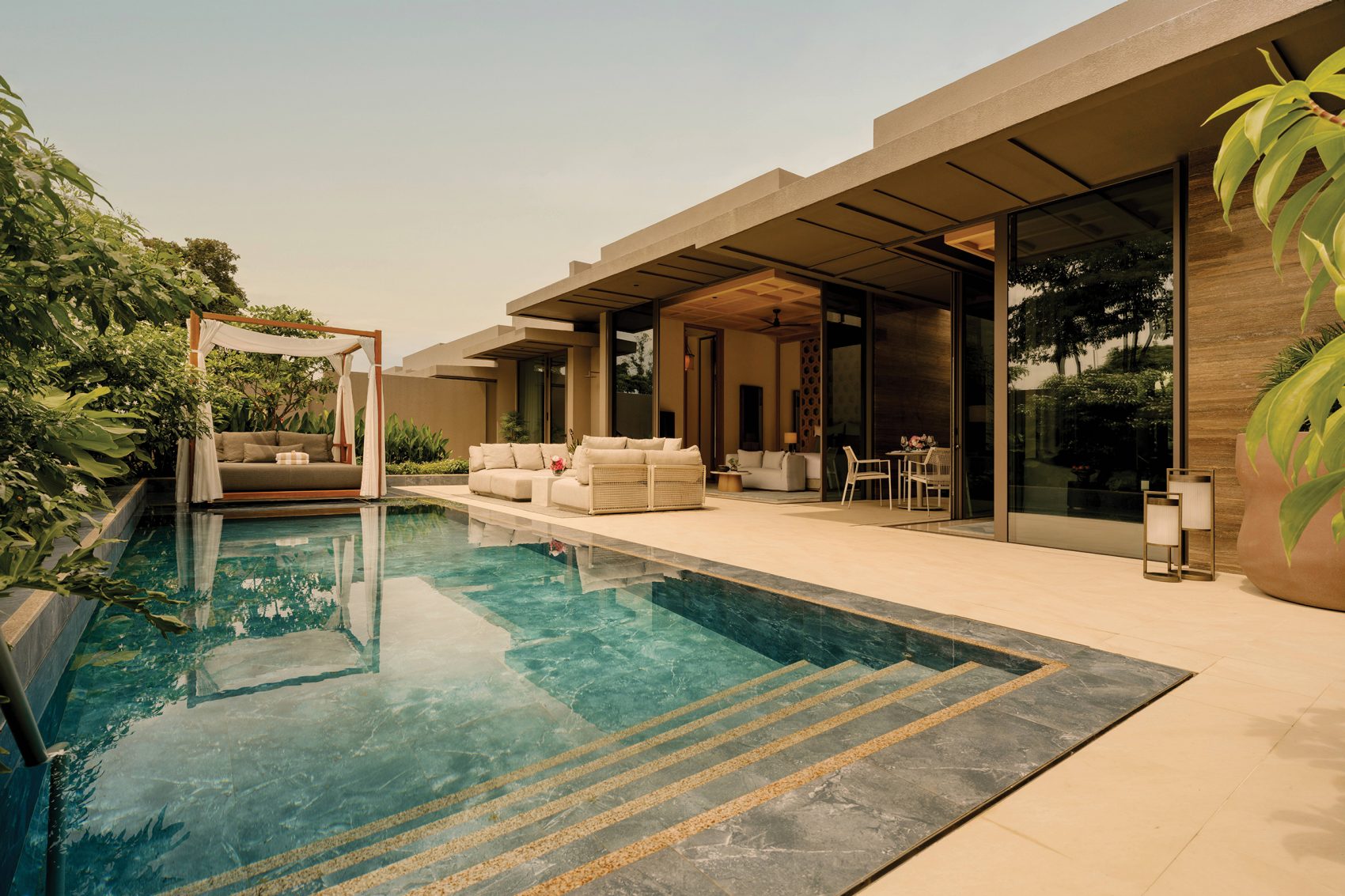 A private cabana and lounge chairs are next to an outdoor pool at newly opened Raffles Sentosa Singapore. 
