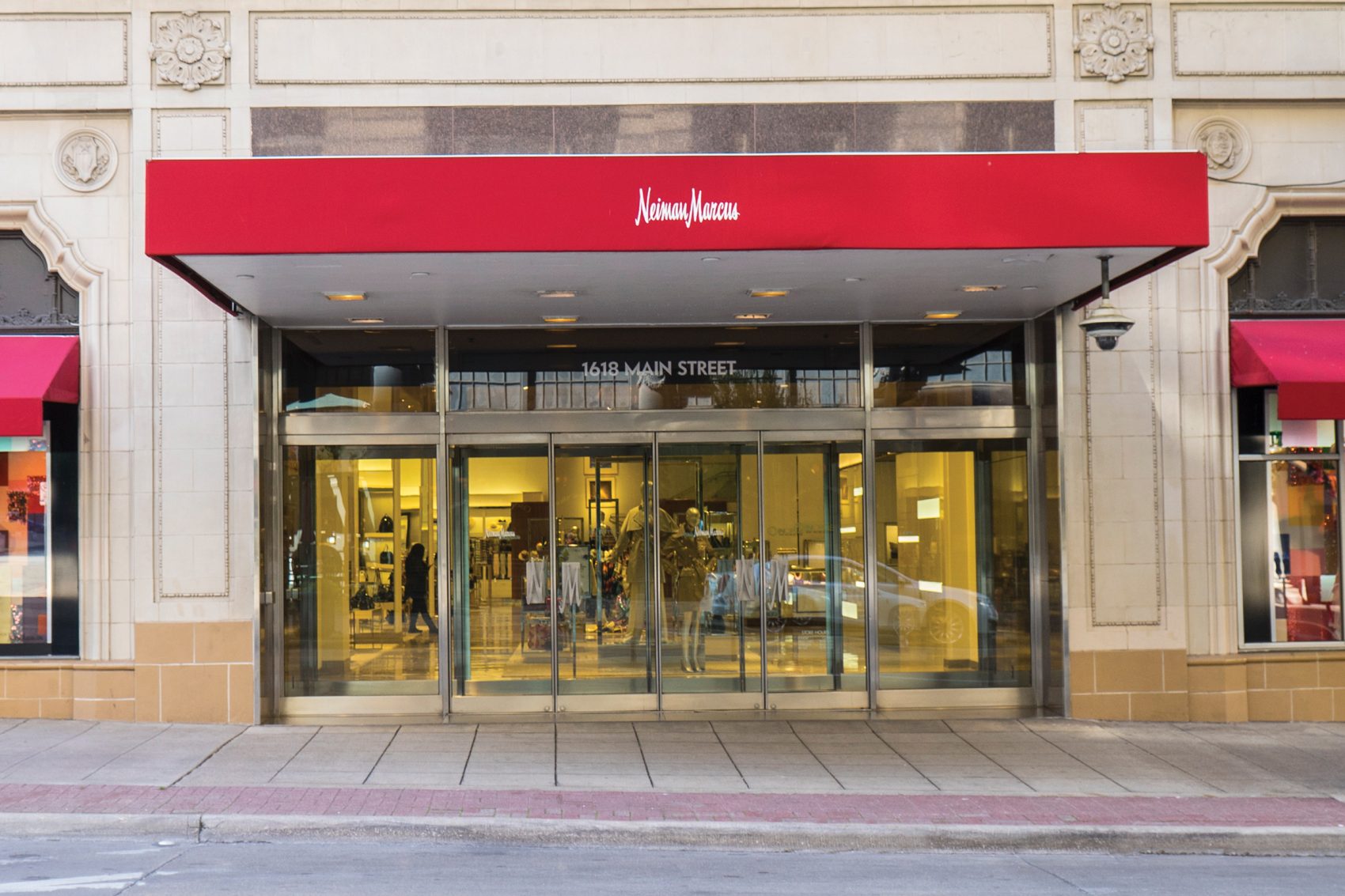 The exterior of Neiman Marcus features a bright red canopy extending over the department store’s main entrance. 