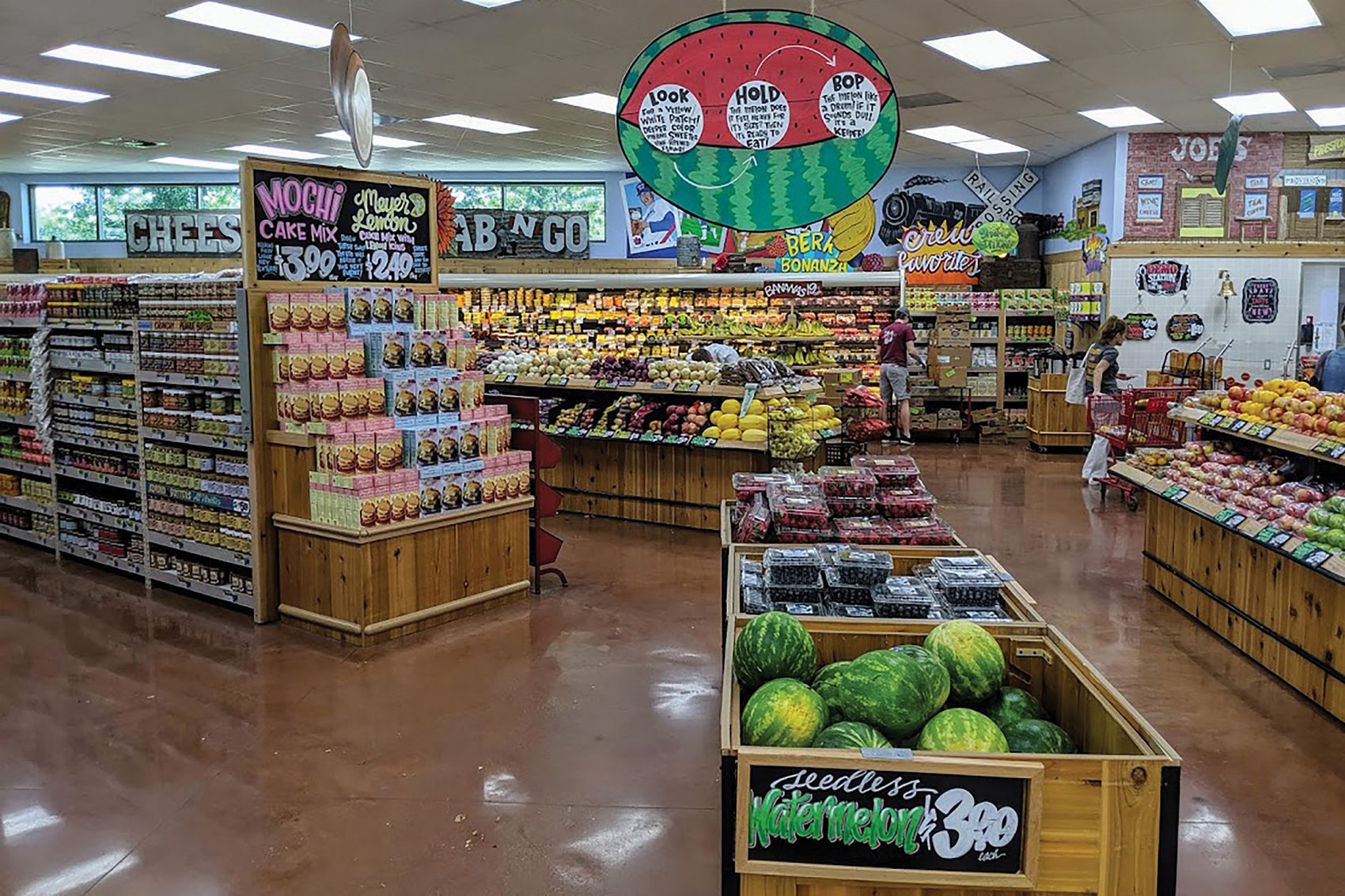 The interior of Trader Joe’s includes boxes and shelves stacked with vegetables, watermelons and other foods.