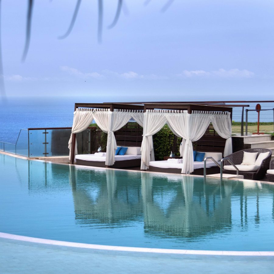 Outdoor pool view and cabanas in the daytime at The Edge, Bali.