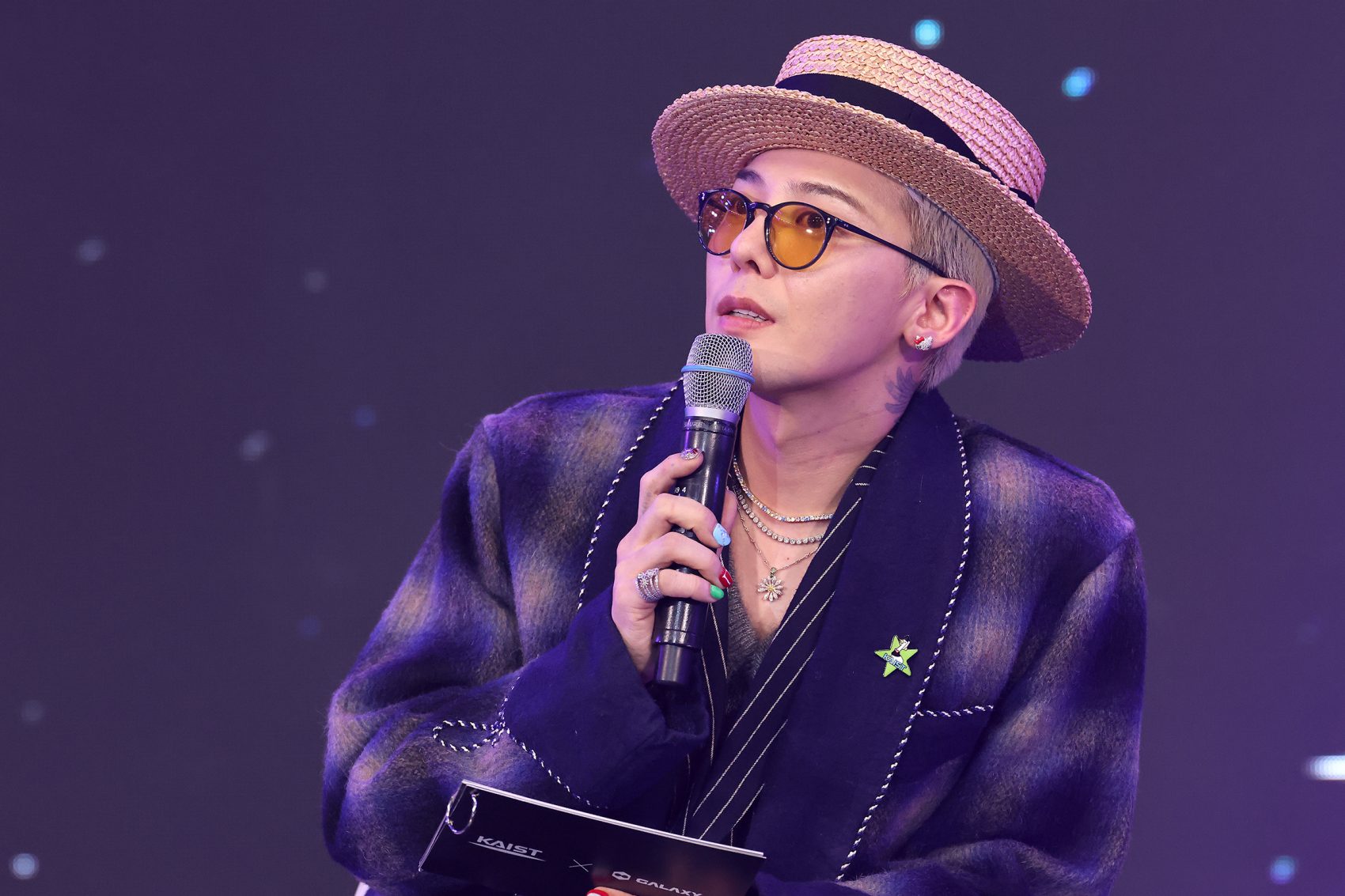G-Dragon, who will be touring Asia in 2025, holds a mic onstage.