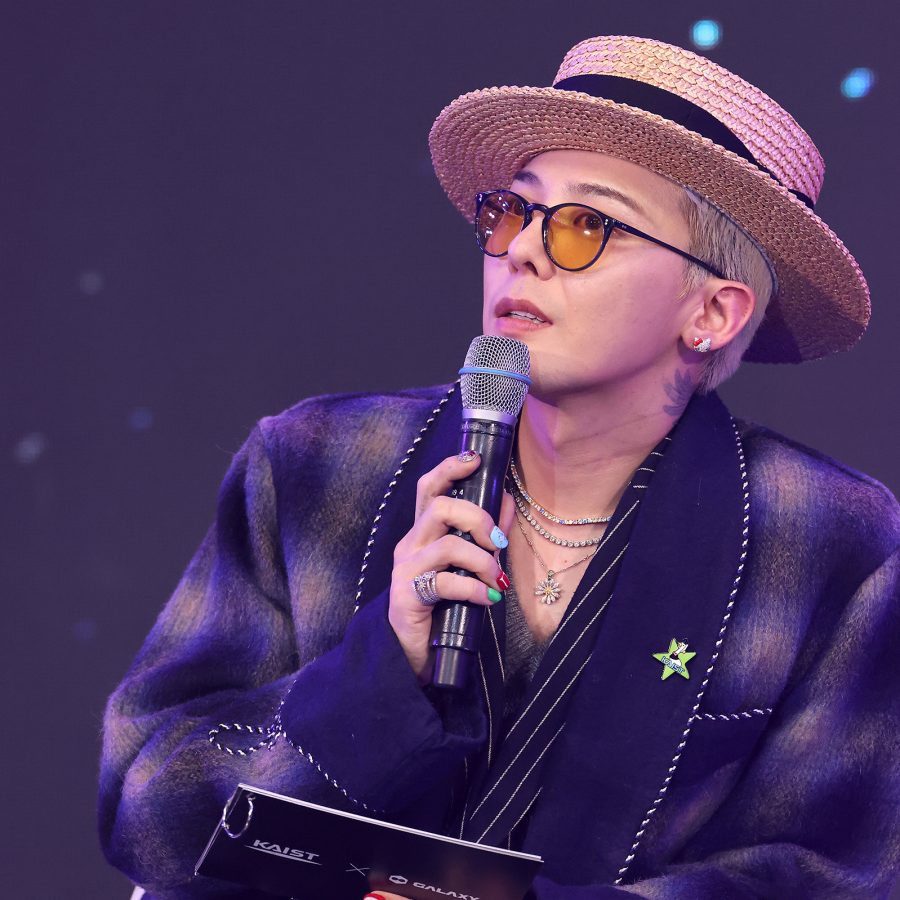 G-Dragon, who will be touring Asia in 2025, holds a mic onstage.