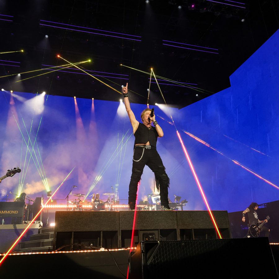 he members of Guns N’ Roses, who are on their 2025 world tour, perform as colourful spotlights illuminate the stage.