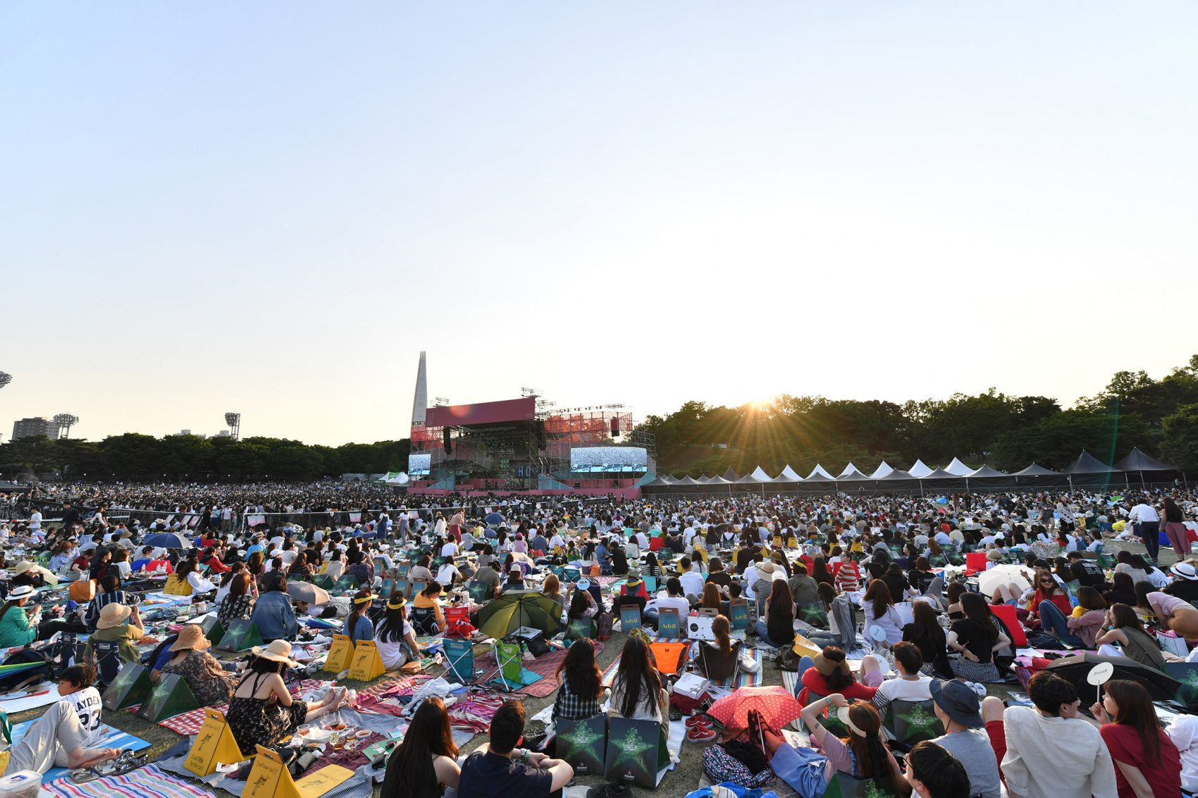 A crowd of people sitting on mats and towels waits in front of a stage at the Seoul Jazz Festival. 