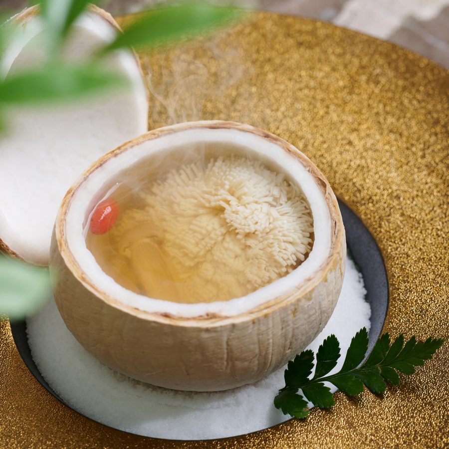 A close up of a steaming hot broth soup served in a coconut at Shanghai Plus in Hong Kong.