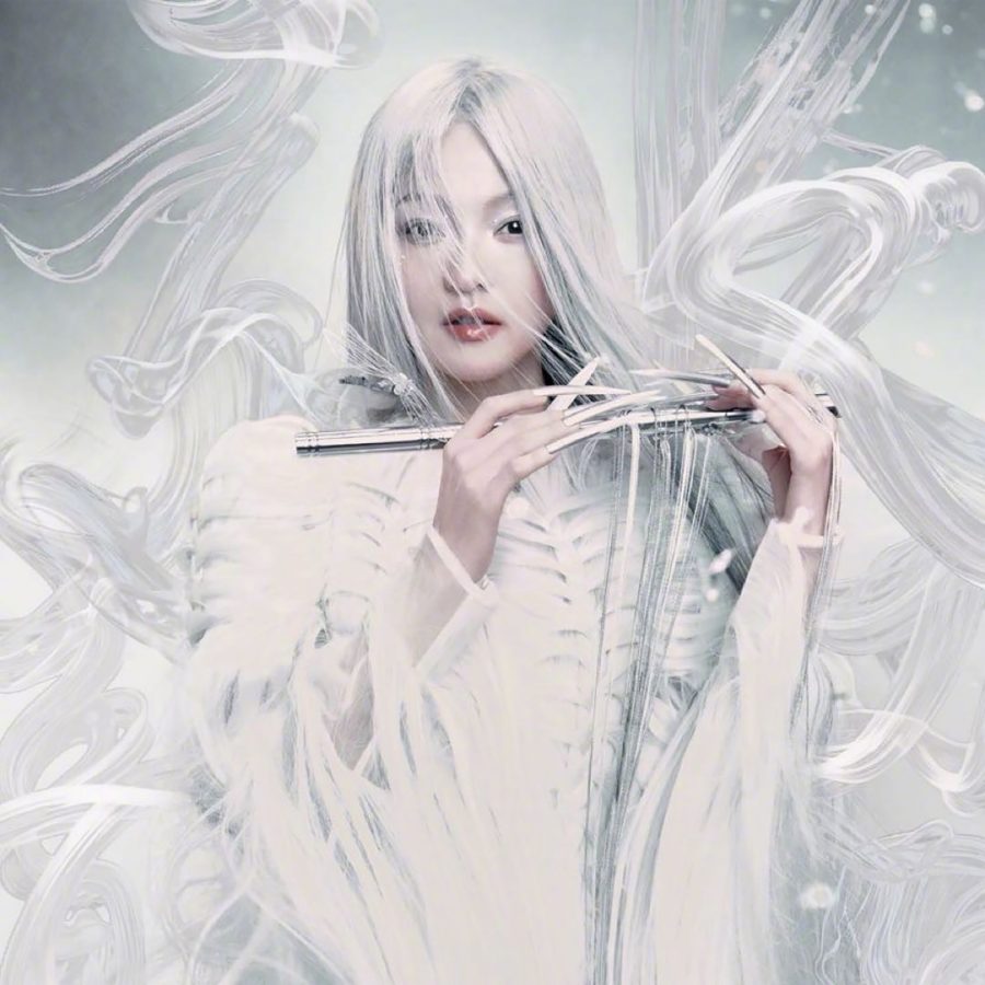 A portrait image of singer Angela Zhang, dressed in all-white and with white hair, holding a flute. 