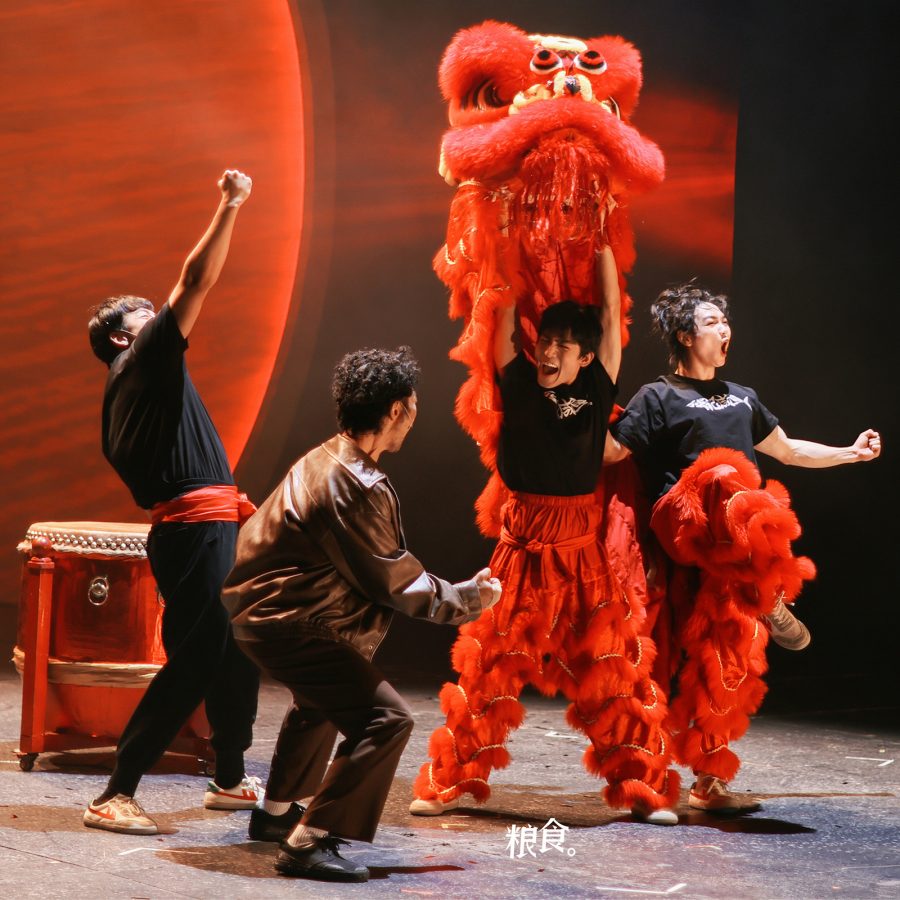 In a scene from the stage drama I Am What I Am, four performers are shown cheering and celebrating. Two of them wear parts of a lion dance costume.