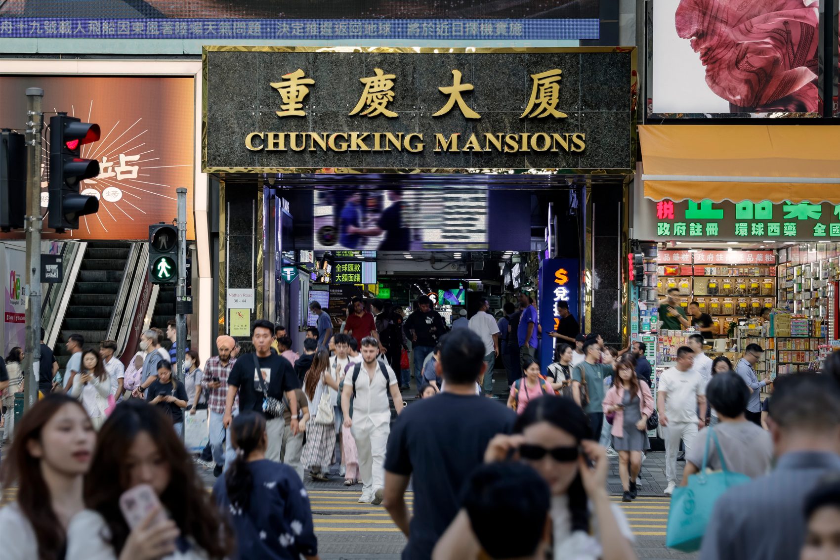 A crowded street view of the entrance of Chungking Mansions during datytime in Tsim Sha Tsui, Hong Kong.