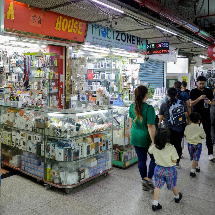 People walking by a line of small shops selling mobile phones and electronics inside Chungking Mansions in Tsim Sha Tsui, Hong Kong.