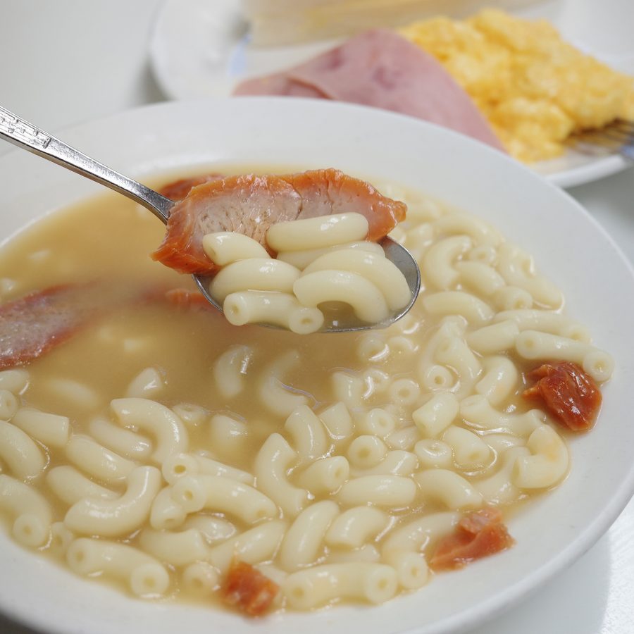 A spoon of macaroni soup being lifted above a larger bowl at Australia Dairy Company. 