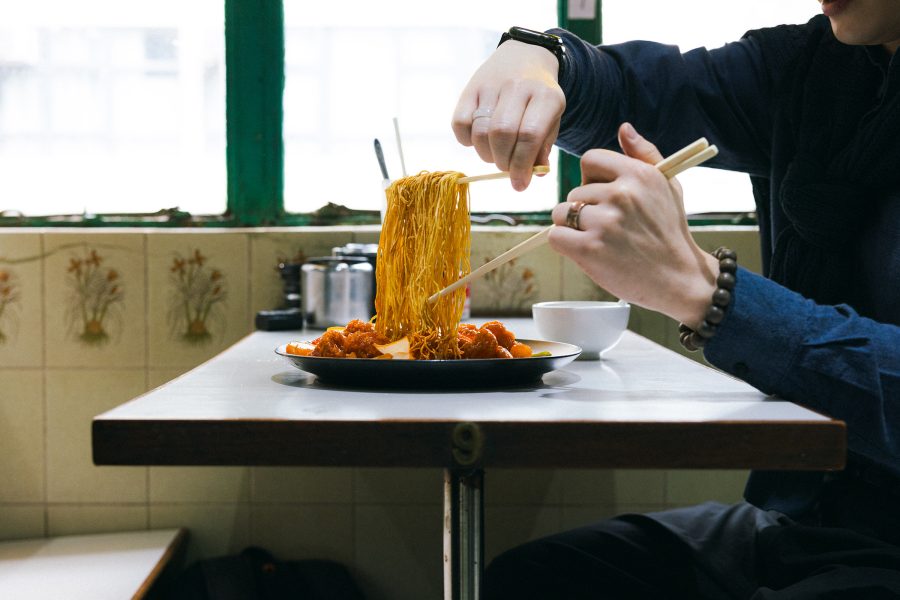Person eats noodles with chopsticks at Mido Cafe in Hong Kong. 