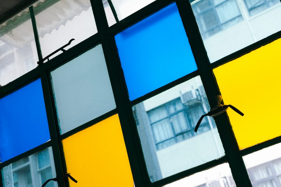 Close up shot of the blue and yellow windows of Mido Cafe in Hong Kong.