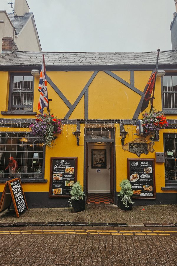 A yellow pub decorated in flowers and flags in Wales. 
