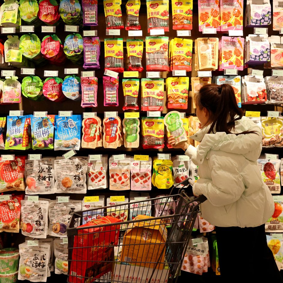 A woman with a shopping cart shops for snacks in a shop in Chengdu.
