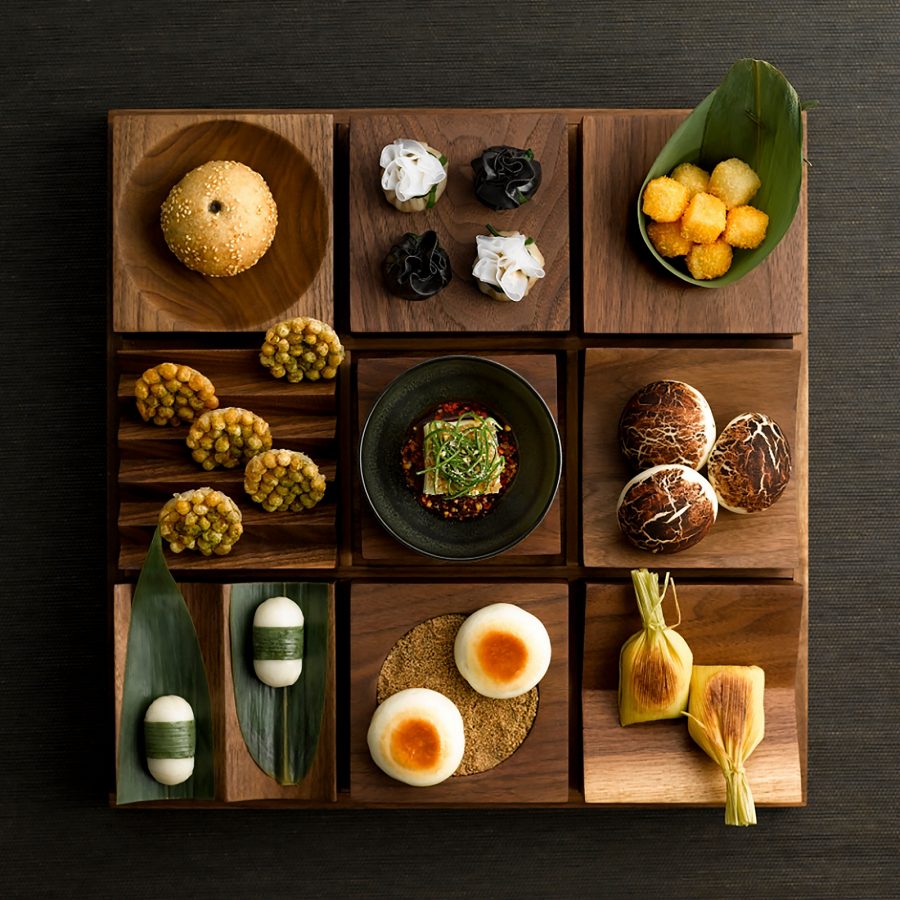 A platter shaped like a 9-square grid is filled with various little bites at The Bridge, Chengdu.