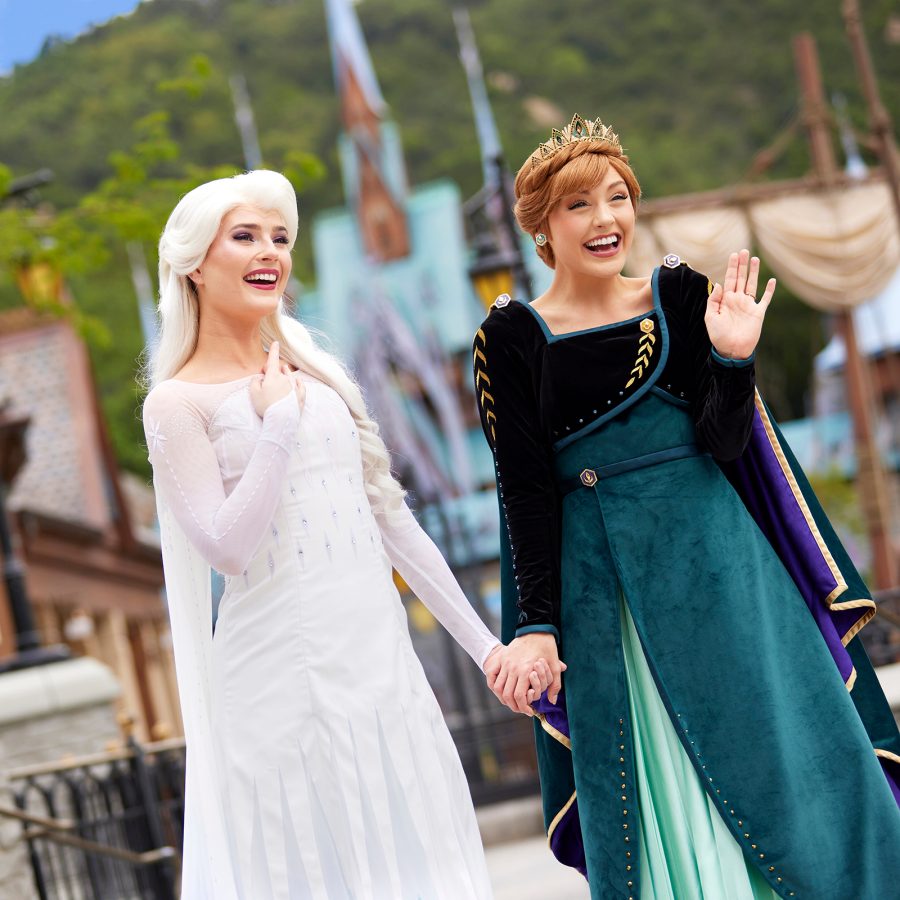 Elsa and Anna from Frozen hold hands as they greet guests at Hong Kong Disneyland. 