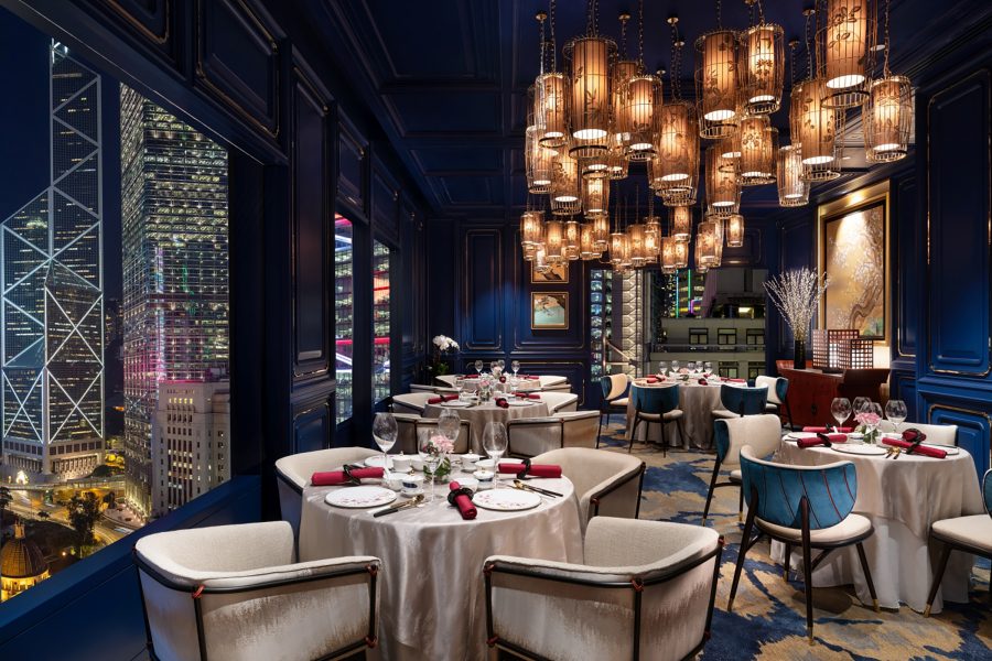 The interior of Mah Wah at night. Hanging lights designed to look like bird cages are softly lit. A large window looks out to illuminated skyscrapers.