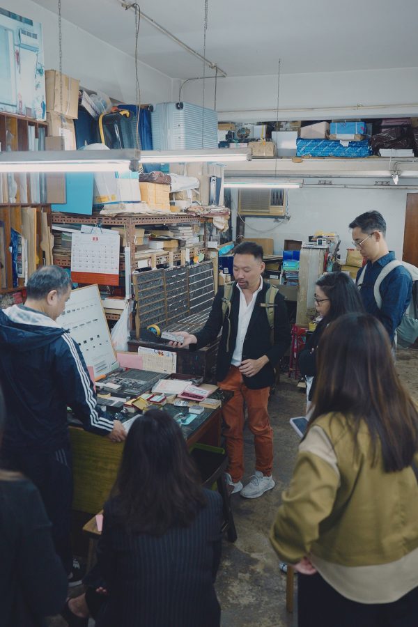 A guide shows a small group of visitors the printing items on display inside the workshop of Kwong Wah Printing Company.
