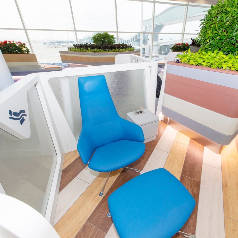A view of a blue padded chair and foot rest at the recharge zone in Hong Kong International Airport.