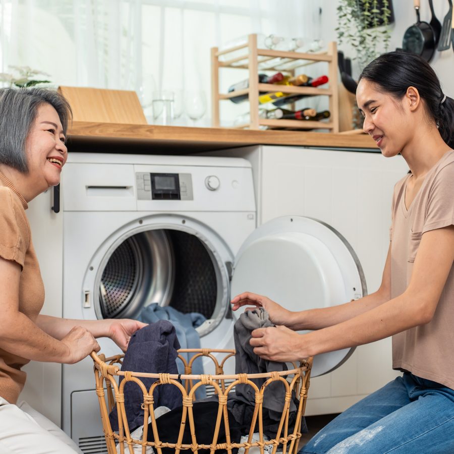 An elderly woman and a domestic helper doing laundry.