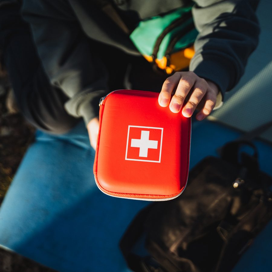 A person holds a red first aid kit.