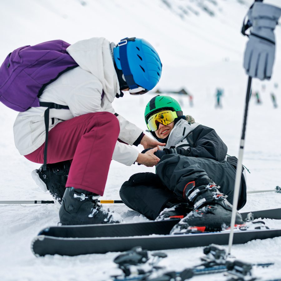 A person helps a skier who has fallen.