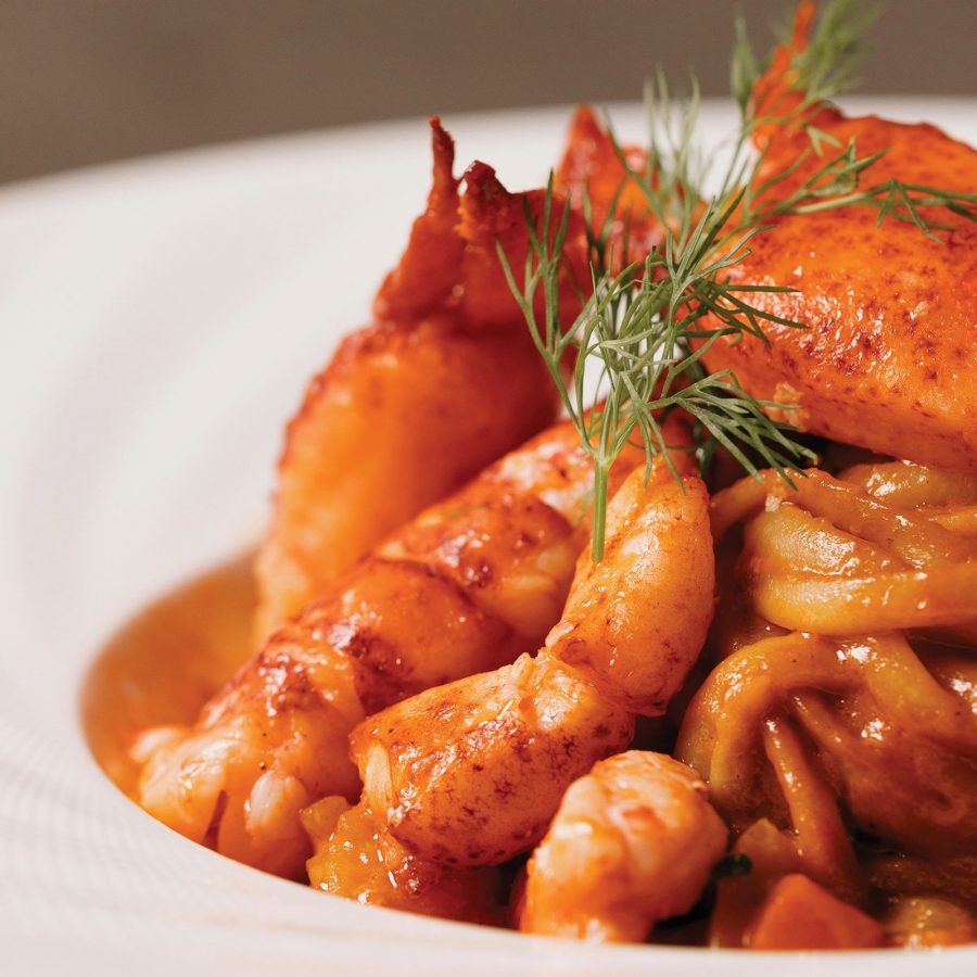 A lobster pasta with red sauce is arranged on a white dish at The Continental.