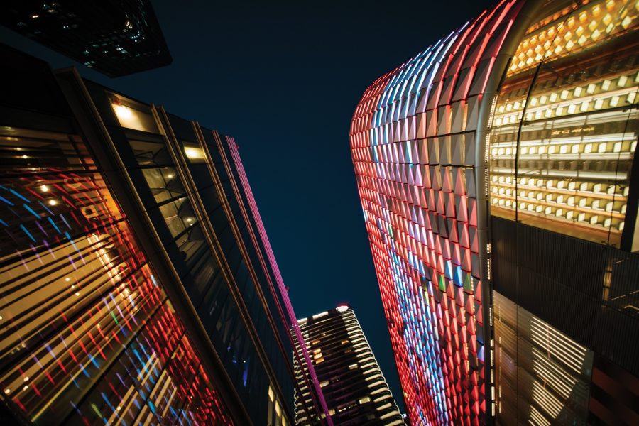  A view looking up towards neon lit skyscrapers in Shenzhen, China at night.