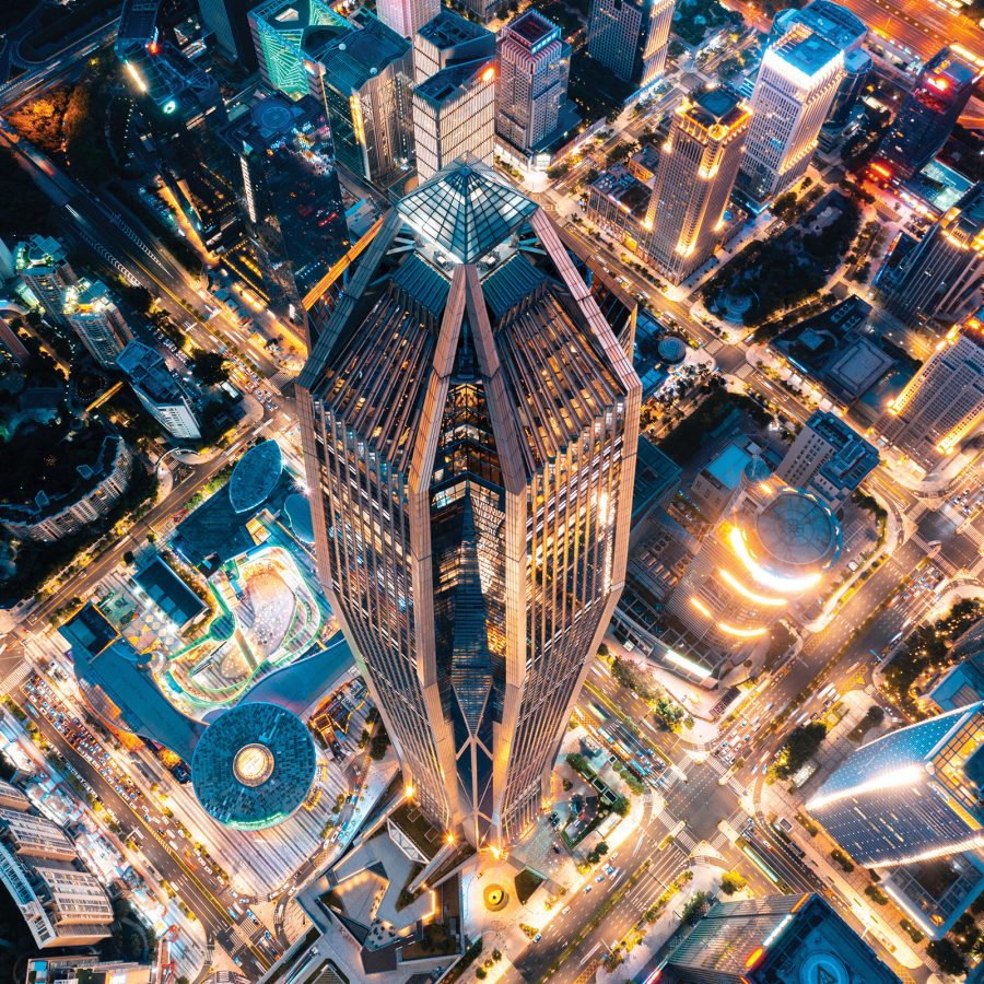 A drone shot of a neon lit city in downtown Shenzhen, China at night and a view of Ping'an International Financial Center from the top.