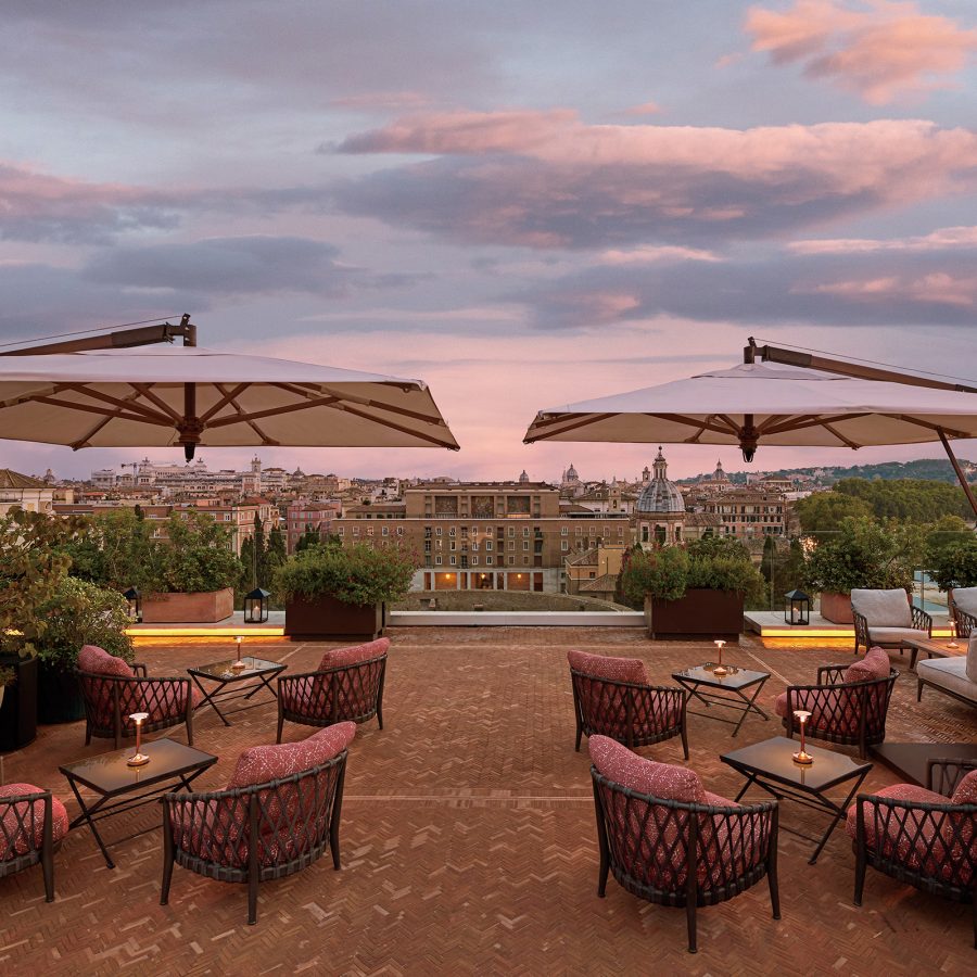 A rooftop lounging area with patio chairs and a beautiful sunset view is accessible for hotel guests of Bvlgari Hotel Roma.