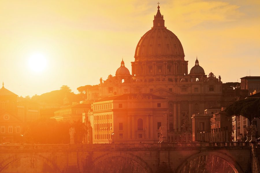 The exterior of St Peter’s Basilica glows orange in the sunset.