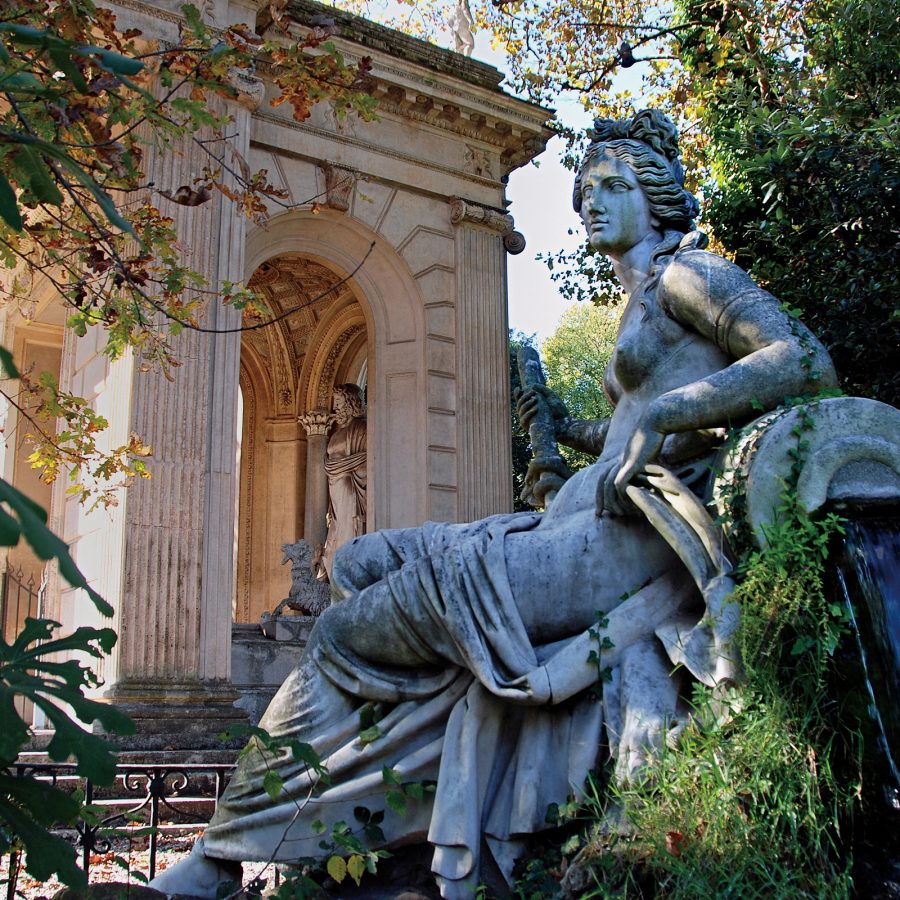 A statue sits in front of a Roman structure at Villa Borghese. 