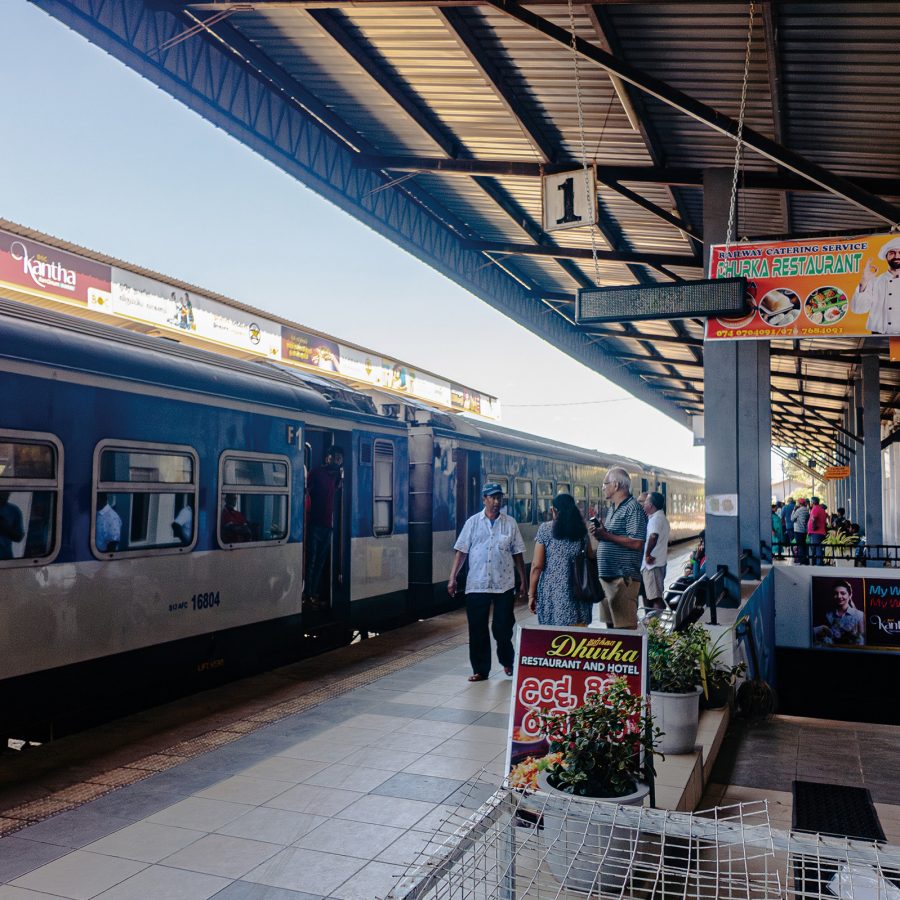 A view of a blue train on the sheltered outdoor platform of the Sri Lanka Railways during daytime