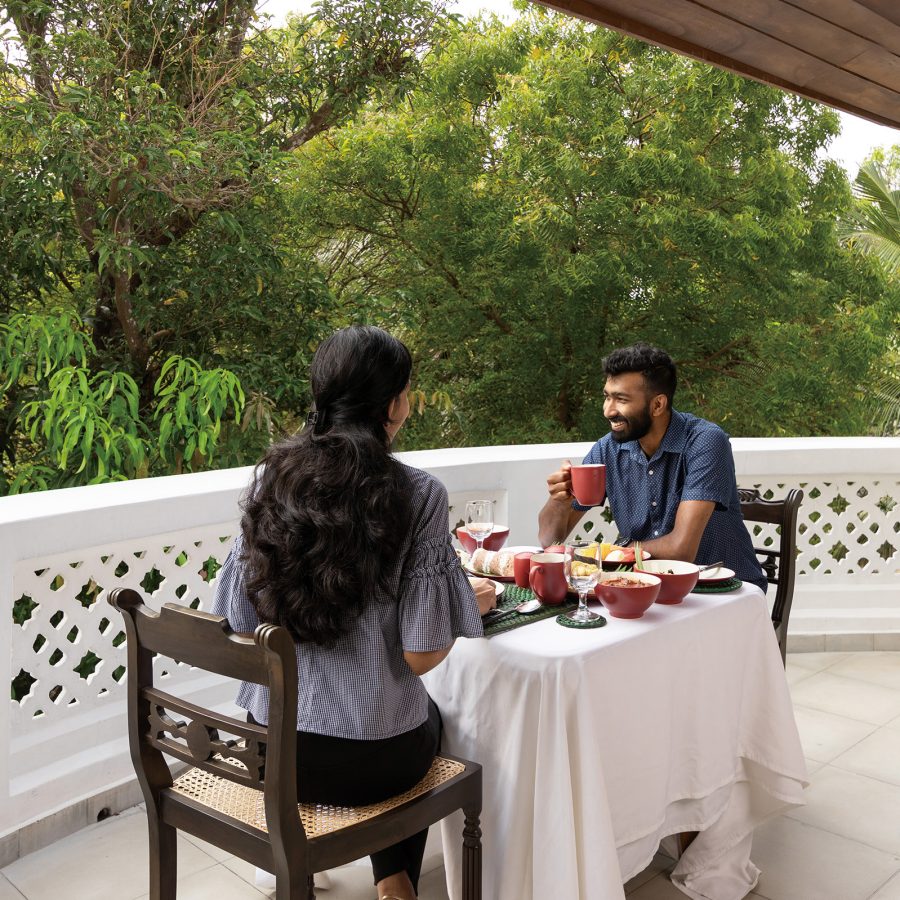 A couple, man and woman, sitting at a table on the balcony, having a meal on a sunny day at Jetwing Mahesa Bhawan in Jaffna, North Sri Lanka