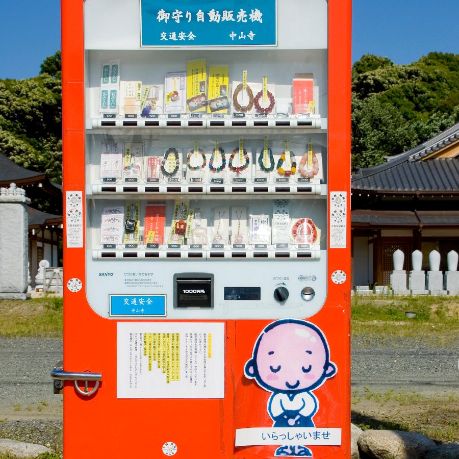 Orange vending machine in Japan full of temple offerings and charms.