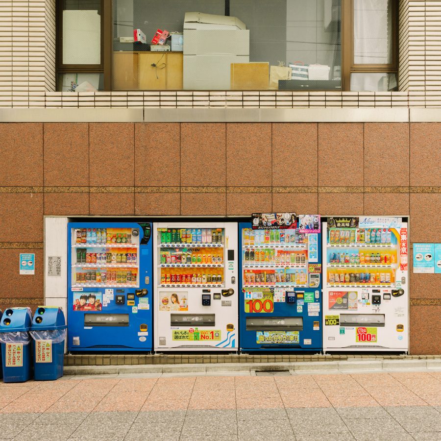 Four blue and white Japanese vending machines lined up in a row.