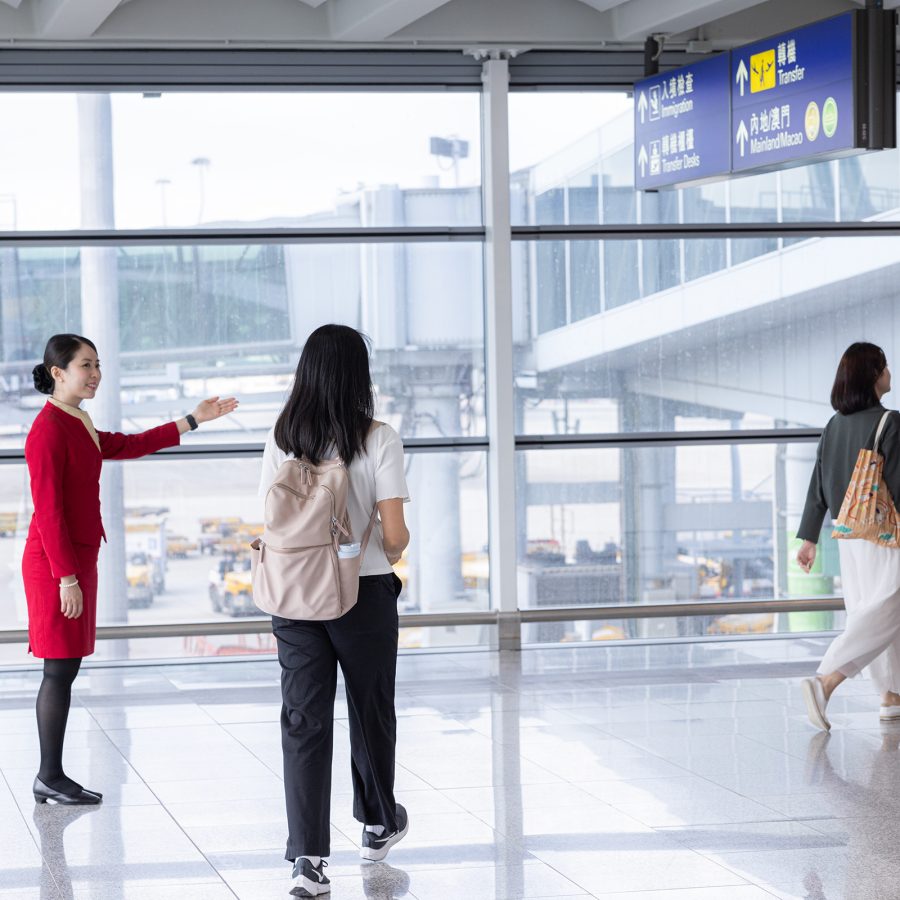 A flight attendant guides passengers from an arrival gate at HKIA.