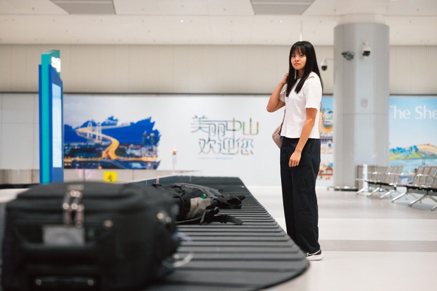 A passenger waits for their bags to come out on a conveyor belt at Baggage Claim. 
